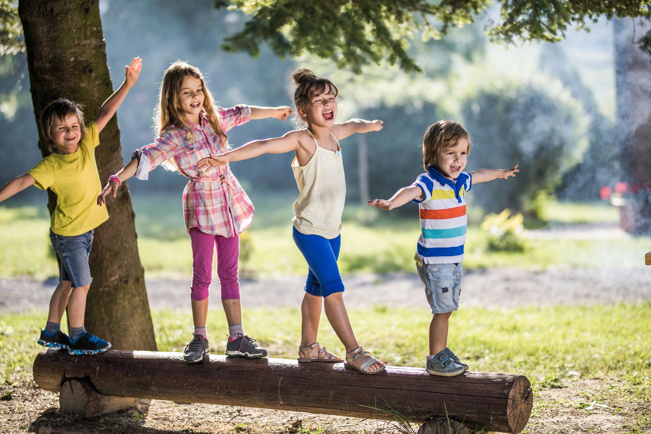 Children balancing on a log in a park