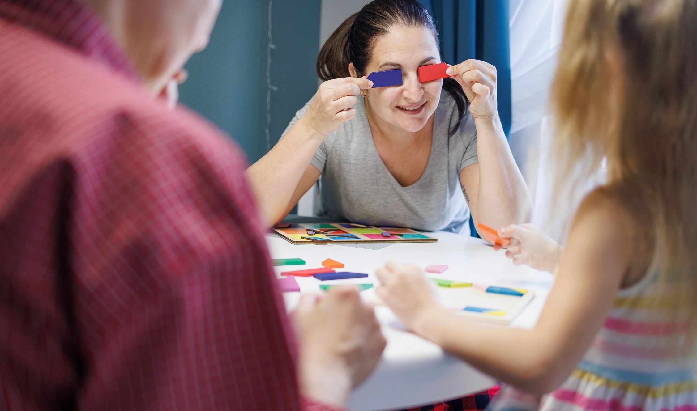 Family playing a tangram puzzle together at a table