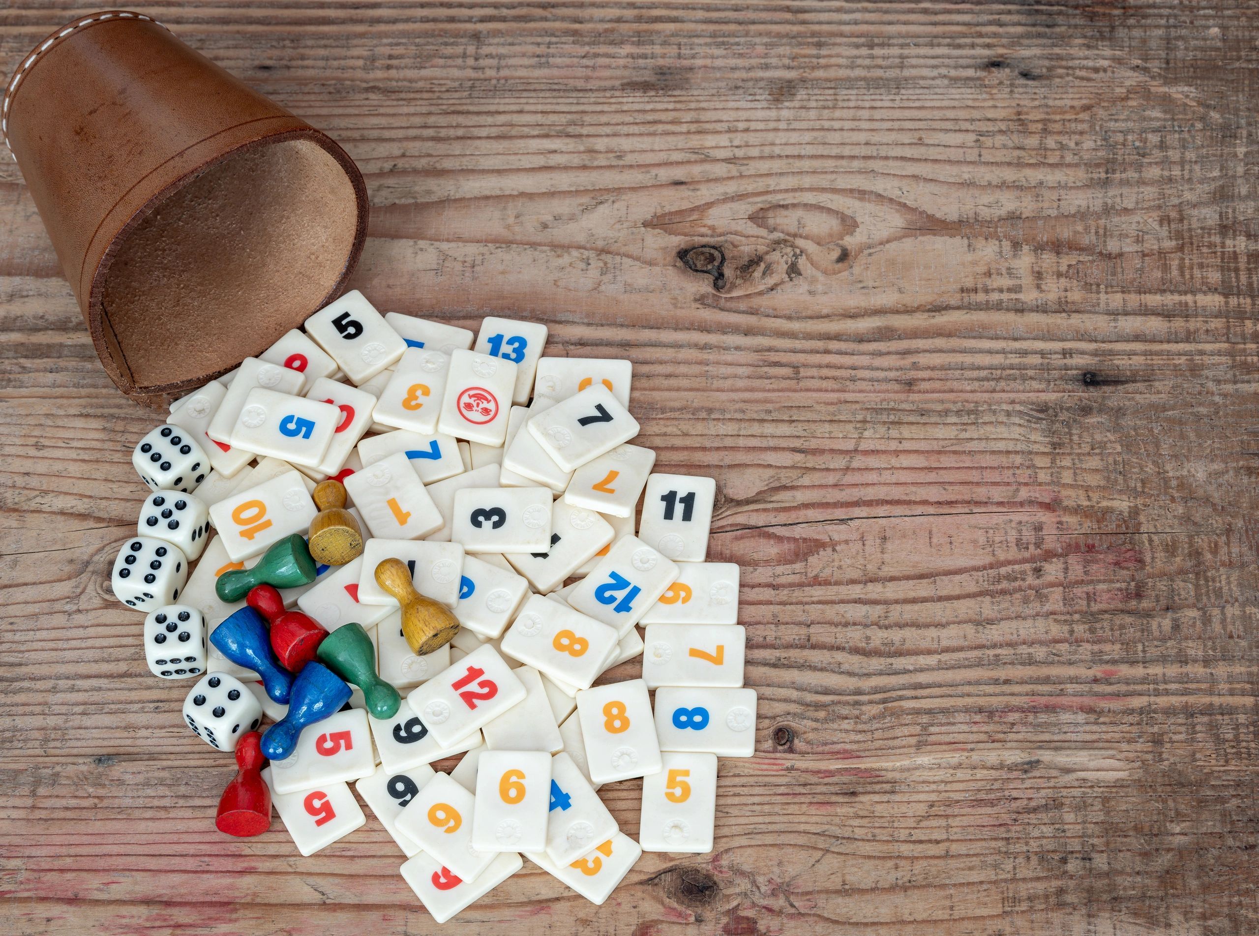 Dice cup and game tiles on a wooden table