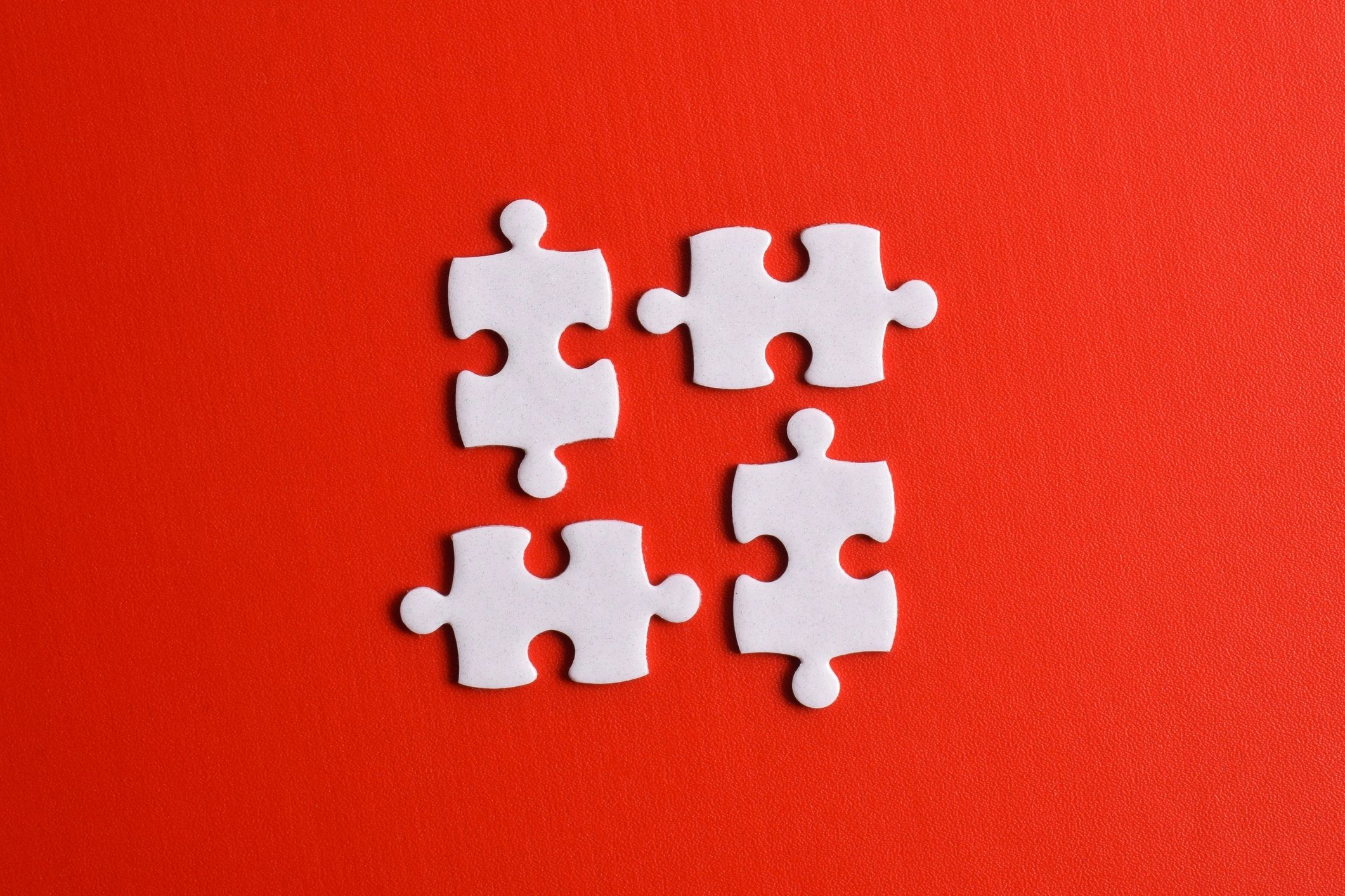 Four puzzle pieces on a red background