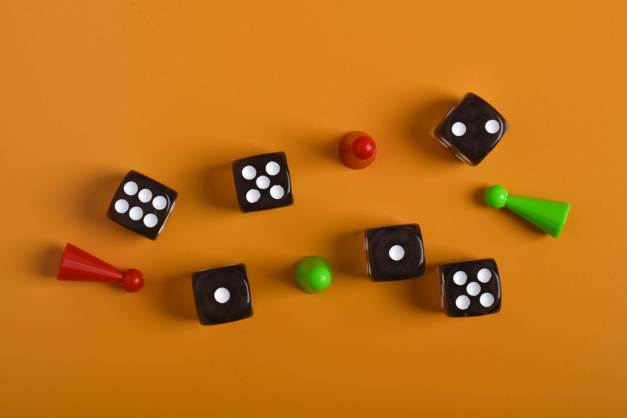 Colorful board game pieces and dice on an orange background