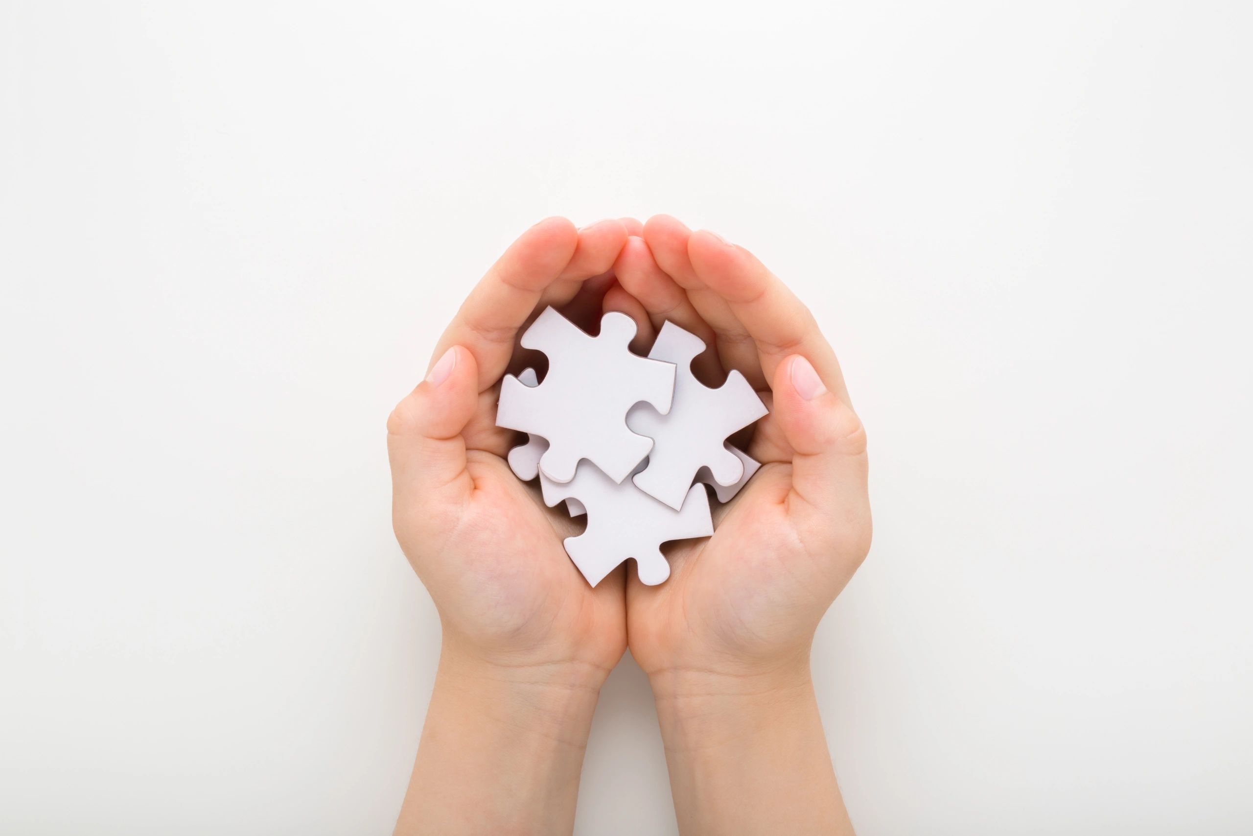 Child holding a heap of puzzle pieces over a table